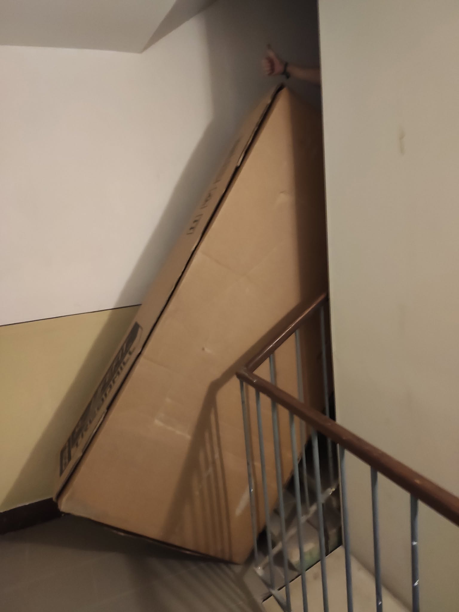 Veľká kartónová krabica bežeckého pásu nakrivená na schodisku bytovky — 8. jún 2020, ráno.
